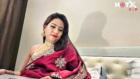 Seductive Indian woman in red saree posing bustily on bed