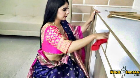Sexy Indian babe in pink saree bends over shelf grabbing red cloth exposing hot navel