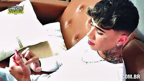 Tattooed gay hunk with piercings teasing pink dildo on couch