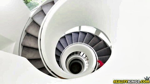 Spiral staircase interior with woman in red shorts at bottom Reality Kings porn scene