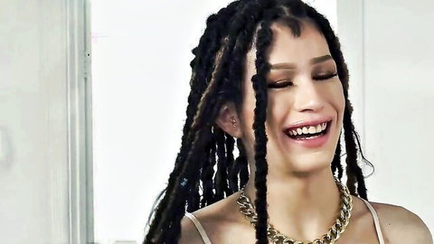 Smiling brunette with braided hair in low-cut top, teasing roommate secrets