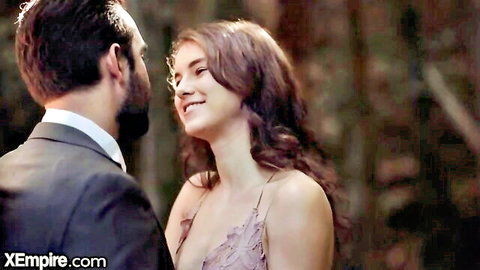 Sensual brunette teen in lace dress smiling intimately at suited bearded man in romantic outdoor gaze