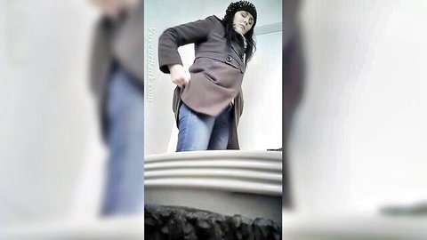 Pale Caucasian woman pulls open gray coat teasing in bathroom mirror voyeur solo