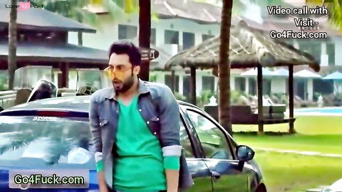 Bearded South Asian hunk in green shirt and sunglasses poses by car at sunny resort during video call