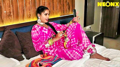 Sexy Indian babe in pink salwar kameez posing seductively on bed with phone teasing tight pussy
