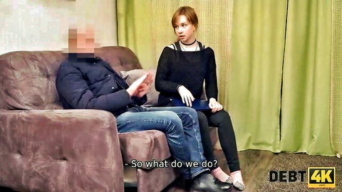 Russian redhead in black sweater and heels negotiates debt on couch with man