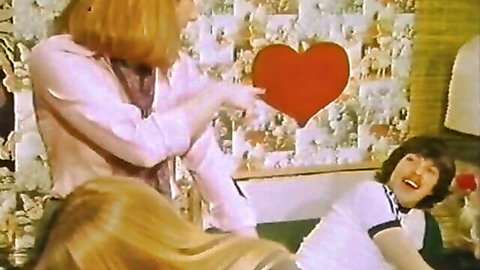 Vintage classic porn thumbnail: long-haired women in pink tops playfully holding heart with smiling man