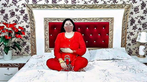 Indian MILF in red traditional outfit sitting seductively on bed