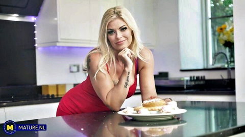 Blonde MILF in tight red dress teasing with donuts on kitchen counter