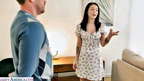 Brunette girlfriend in short floral dress gesturing to boyfriend in living room