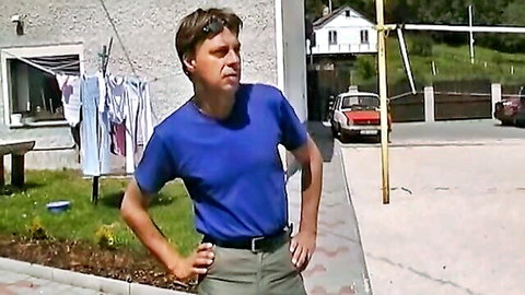 Clothed man in blue t-shirt and khaki pants stands hands on hips outdoors teasing