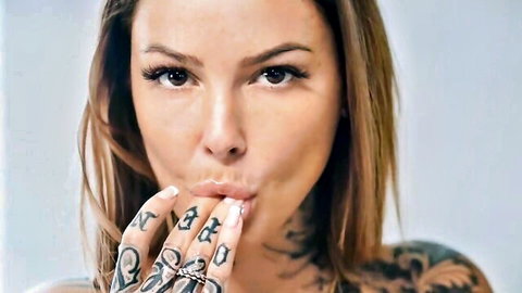 Tattooed babe puckers glossy lips blowing seductive kiss with inked fingers