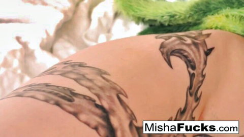 Tattooed nude woman gripped by green furry alien monster tentacles on her back and hips