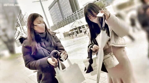 Two masked Asian women in winter coats chatting outdoors, hinting at steamy roleplay encounter