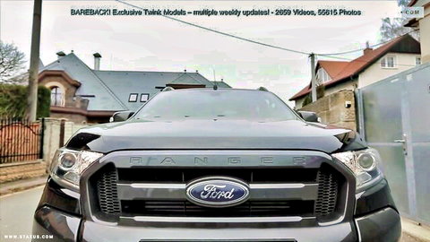 Shiny black Ford Ranger truck front grille parked on street with houses