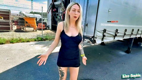 Blonde tattooed Lisa Sophie in tight blue dress posing outdoors