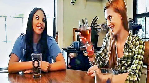 Brunette Latina and redhead best friends smiling with drinks before lesbian orgy