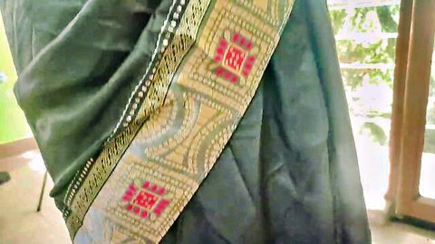 Indian woman in elegant green saree with gold embroidery posing sideways by window