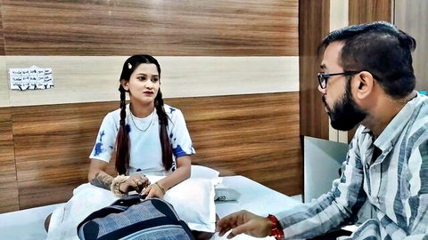 Indian girl with pigtails in white top sitting on bed smiling at bearded boyfriend