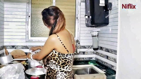 Desi model Antim in leopard print dress washing dishes from behind, teasing kitchen hookup