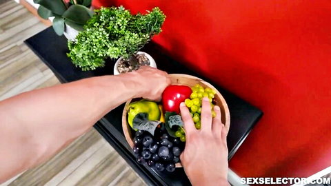 Bella Scorpion's hands holding colorful fruit basket, teasing adult scene preview