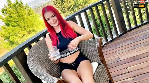 Redhead Faribanx in black crop top and shorts on balcony, smiling with navel piercing