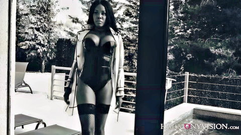 Curvy black woman in black lingerie, stockings and high heels posing outdoors