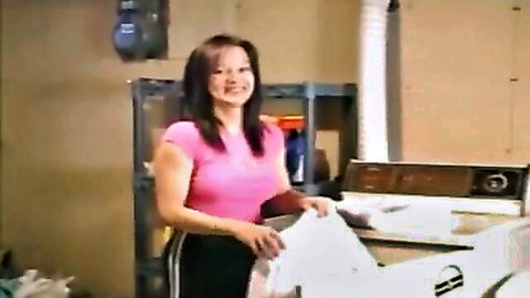 Smiling hot Asian wife in pink tank top holding laundry seductively
