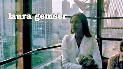 Laura Gemser in white blouse, long hair, overlooking city in vintage Emanuelle scene