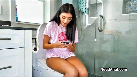 Hot brunette girlfriend on toilet in pink tee, smiling at phone