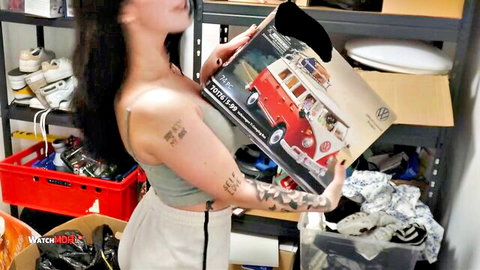 Roxy Black with big tits and tattoos holding VW van box, teasing cleavage
