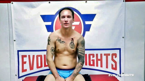 Jason Michaels shirtless in blue briefs, tattooed fighter for Evolved Fights sexfight with Nadia White