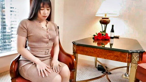 Seductive Japanese MILF in tight beige knit dress sitting teasingly in luxury hotel room