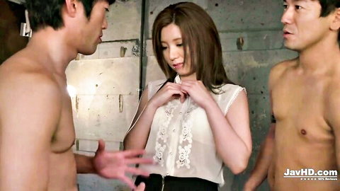 Smiling Japanese brunette unbuttons lace blouse surrounded by two shirtless muscular Asian hunks in locker room threesome tease