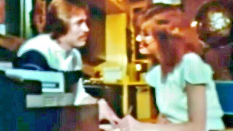 Vintage redhead babe in office leaning close to seduce shaggy-haired guy during interview
