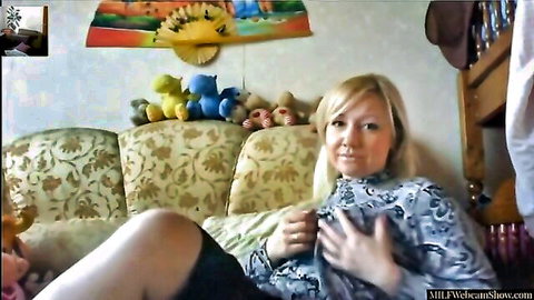 Blonde MILF teases on webcam, hand on chest in patterned dress
