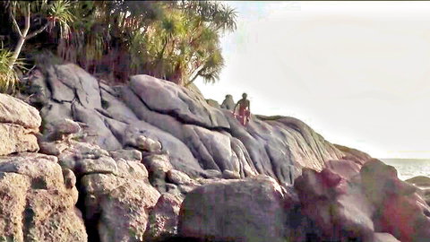Hot couple in rough embrace on rocky beach during intense outdoor public sex at sunset