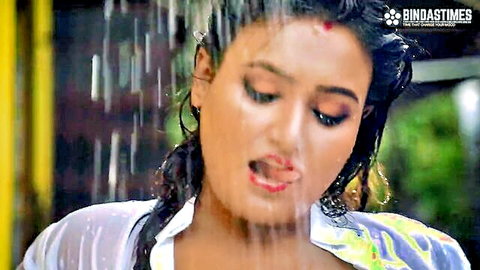 Wet Indian beauty in sheer transparent shirt pouting seductively in outdoor rain shower