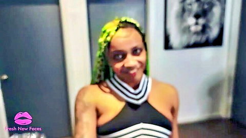 Ebony babe with neon green braids smiling and teasing deep cleavage in striped halter top