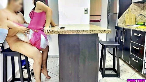 Petite Latina in tiny pink tutu skirt sits on kitchen stool as naked man rubs big hard cock on her ass