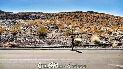 Brunette woman running outdoors in desert along road with hills