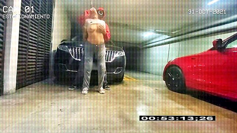 Topless Latina flashing huge tits in underground parking garage with cars and hooded guy