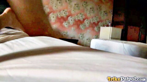 Bare muscular leg and foot dangling over white bed sheets in floral pink bedroom POV