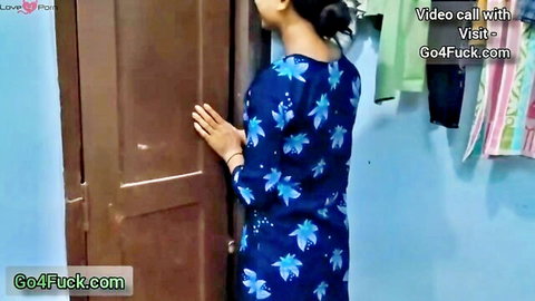 Sexy Indian college girl in blue floral dress standing by door during video call