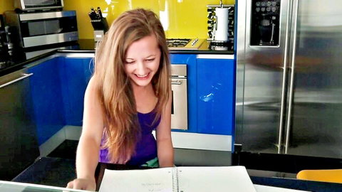 Smiling 18yo nubile brunette in purple tank top at kitchen counter