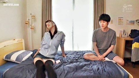 Asian couple on bed, girl in hoodie, skirt and thigh-high stockings teasing