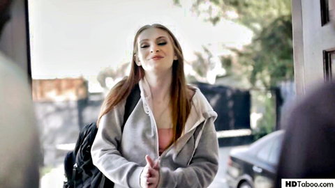 Maya Kendrick smiling in open gray hoodie, natural redhead beauty outdoors