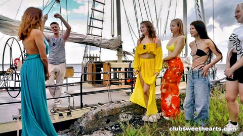 Group of bikini-clad women and man partying on yacht deck, nauti vibes