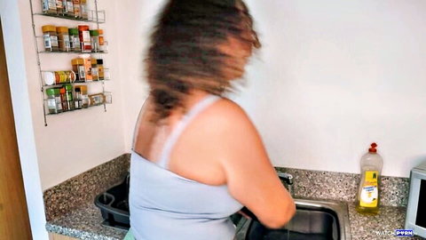 Brunette MILF with huge ass in tank top and shorts washing dishes at kitchen sink