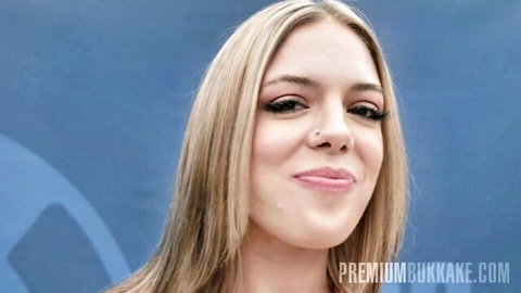 Young blonde with long hair smiling seductively before bukkake group cumshot